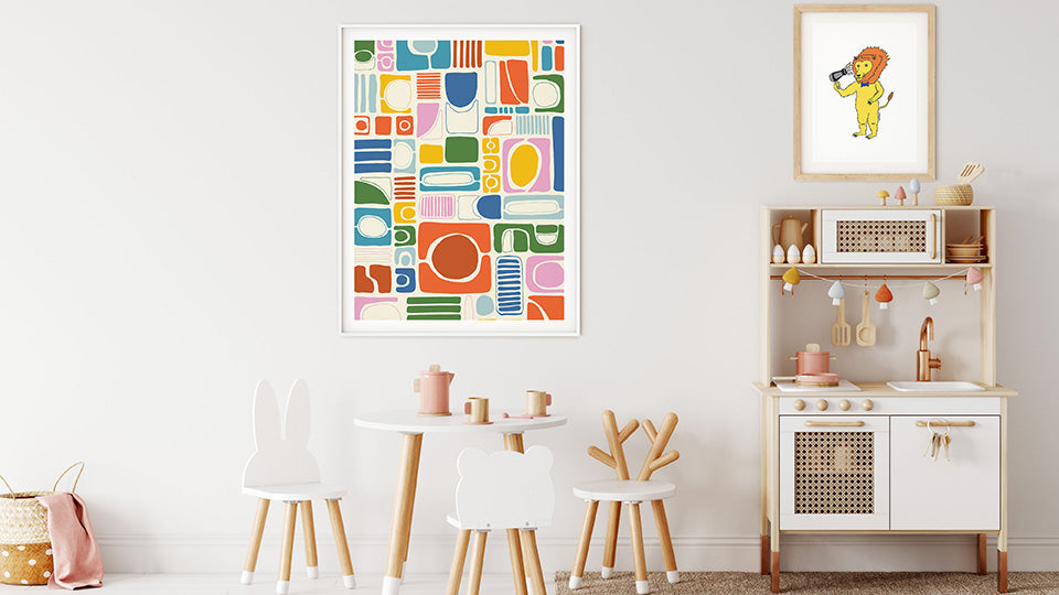 Two framed nursery wall art prints featuring geometric abstract art and a cartoon lion, displayed above a cozy crib in a baby nursery with soft, neutral decor