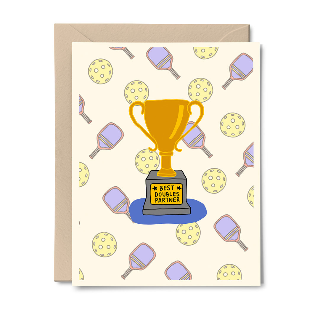 Greeting card featuring a gold “Best Doubles Partner” trophy surrounded by pickleball balls and racquets, digitally illustrated by Erwin Ong.